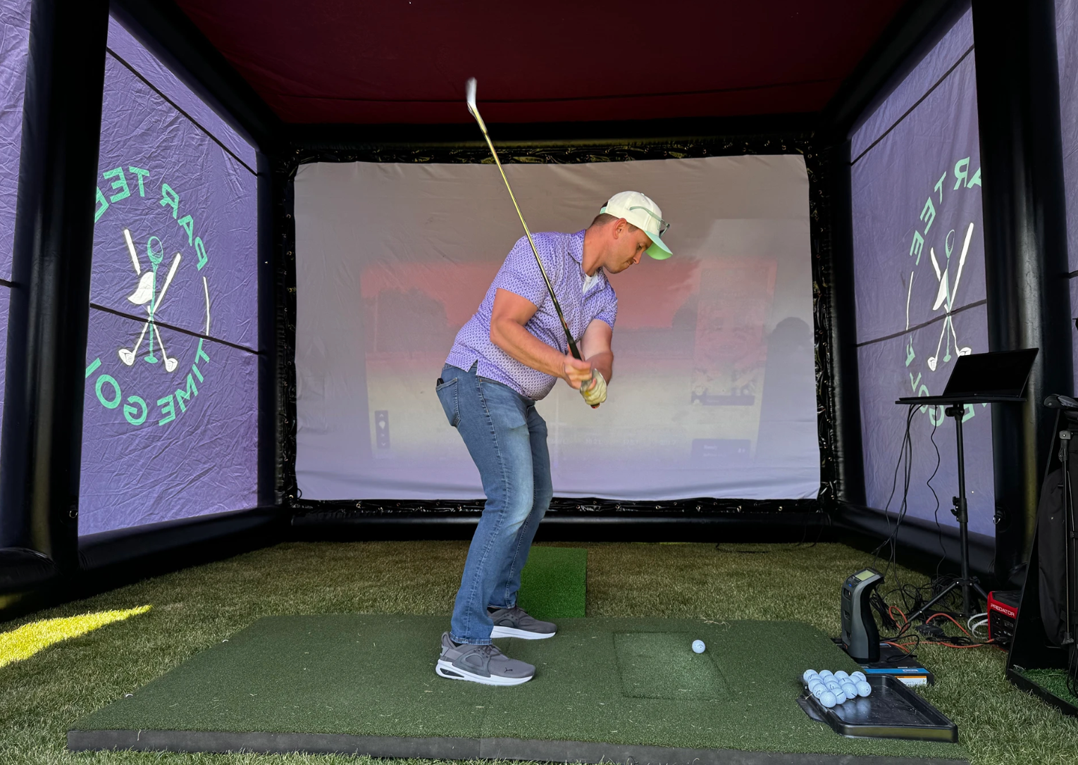Guest swinging inside the Swing Suite mobile golf simulator bay